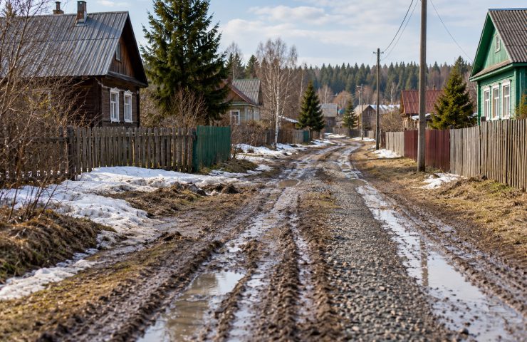 Деревенская грунтовая дорога с колеёй и талым снегом