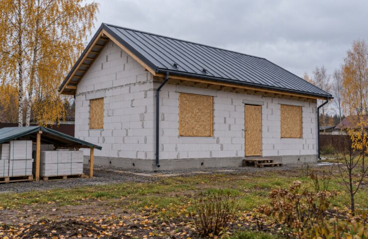 Недостроенный дом под кровлей с временной защитой проёмов перед зимой